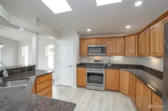 The kitchen features an abundance of beautiful cabinets, with a pantry conveniently situated to the left of the stove and oven. Gorgeous new flooring has just been installed, adding a fresh touch to the space.