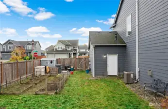 East side of backyard; gate to driveway, more garden space, door to garage.