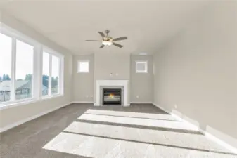 Similar home, not actual. Living room features gas fireplace with tile surround and ceiling fan.