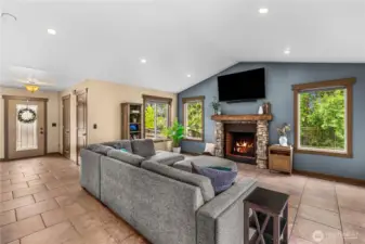 Bright living room with stone fireplace, large windows, and serene views.
