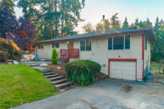 Front walkway and stairs lead to the covered main entry, framed by a cheerful red railing and established shrubbery—creating a warm and welcoming first impression.