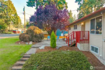 A charming sitting area under the shade of mature trees offers the perfect spot for morning coffee or evening relaxation. This low-maintenance front patio enhances curb appeal and extends outdoor living space to the front of the home.