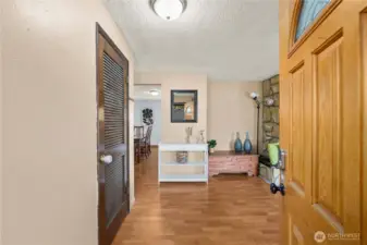 A welcoming entryway opens directly into the expansive main living area, setting the tone for the home’s open and connected layout. Durable flooring and neutral tones create a warm first impression, while the nearby stone fireplace immediately draws the eye—hinting at the comfort and character found throughout the home.
