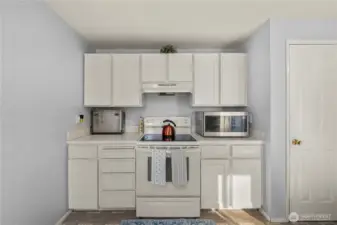 Cooking zone features an electric range with vent hood, a bank of drawers for utensils, and a nearby closet pantry for extra storage.