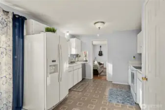 Opposite angle shows the full-size refrigerator niche and wide walkway, ensuring easy traffic flow between the kitchen, dining area, and deck—ideal when multiple generations share the space.