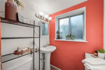 Bright and efficient bathroom space includes a pedestal sink, updated lighting, and a large window that adds natural light—perfect for guests or extended-stay family members using the lower level.