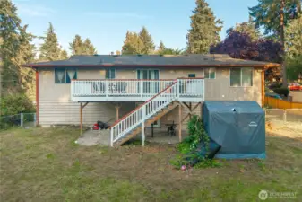 Rear elevation showcases the full deck with stairs leading to the open yard below. A perfect layout for indoor-outdoor living, weekend barbecues, or watching kids and pets play while enjoying the sunset from above.