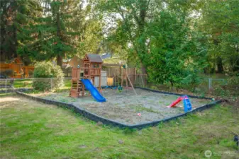 Dedicated play space complete with swing set and slide, bordered for safety and easy maintenance. A dream setup for outdoor fun with plenty of room to grow alongside your needs.