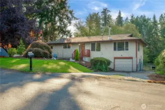Gently sloped front yard leads to the main entrance and driveway with basement-level garage access. Mature landscaping and clean lines make this home both inviting and functional for everyday living.