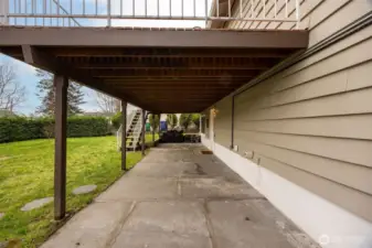 Patio area under the deck; and stairs back to the deck. Lower level entry on the right, at the mat.