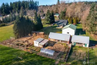 Multiple outbuildings including a 30'x48' shop with office and bathroom, 24'x74' barn, covered lean-to, greenhouse and fenced in orchard with pond and water feature.