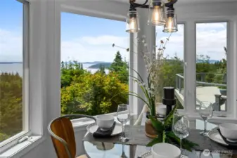 Charming dining nook wrapped in windows—enjoy meals with sweeping views of water, trees, and sky.