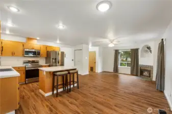 Second view of open concept kitchen family room with new stainless steel appliances and sink with kitchen island and more new lighting.  Did we say all hard wood flooring on main level for easy maintenance also?
