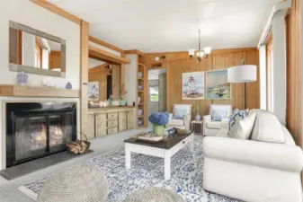 Family room with vaulted ceilings, fireplace and sliding door to west facing deck with lake views.  Opens to kitchen.  Virtually staged photo.