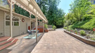 A beautiful paver patio with custom-made raised flower beds seamlessly extends your living to this tranquil and mature yard, connecting different areas with ease and providing convenient access.
