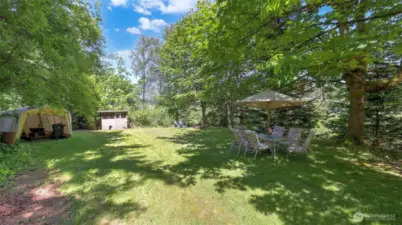 Spacious yard offers a variety of uses with different areas throughout - enjoy this open area for pets, gatherings, and outdoor fun. Includes storage space for tools and equipment, a handy shed, fire pit, plus room for tables and chairs to unwind and entertain.