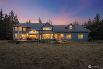 Twilight view of the back exterior with expansive deck.