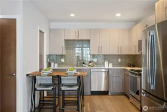 Gourmet kitchen with tile backsplash, quartz counters, stainless steel appliances, induction cooktop, and walk-in pantry.