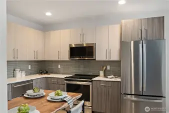 Gourmet kitchen with tile backsplash, quartz counters, stainless steel appliances, induction cooktop, and walk-in pantry.
