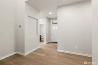 Entry way looking back to designer front door with decorative transom glass inlay showcases hallway niche and hardwood floors.