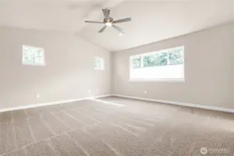 Large primary bedroom featuring a standard ceiling fan and soft carpet for comfort.
