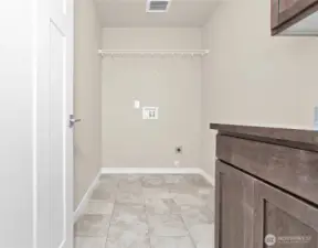 Separate laundry room with a counter, storage cabinets and a storage shelf above appliances.