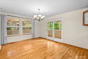Spacious dining with warm hardwood flooring and french doors leading to the covered porch