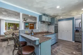 Open breakfast bar, beautiful vinly plank  floors, tile backsplash, gas range and hood,  and views to both the front and back of the  home.