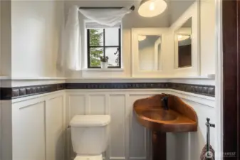 Copper sink and lighting, wainscoting and copper toned tile grace the updated powder room