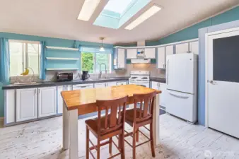 Open plan kitchen with newer counters, faucets and lighting.