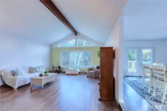 As you enter, vaulted ceilings and an abundance of natural light create a bright, airy feel. The primary living area flows seamlessly, with an open kitchen and dining space to the right.