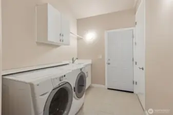 Laundry room with deep sink, door to 3 car garage and access to upper level bonus room.