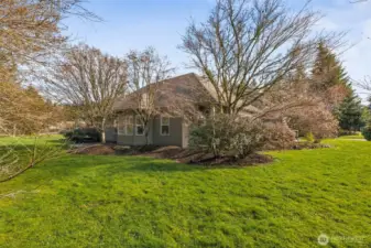 View of home from one of the property corners in the back.  Covered patio off of primary suite.  Mature landscpaing.