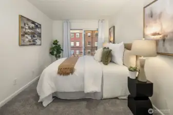 Primary bedroom has cool neutral tones and a slider door to a private balcony.