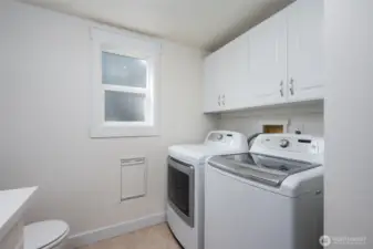 Lower-level half bath with washer and dryer, offering easy potential to convert to a 3/4 bath thanks to existing plumbing.