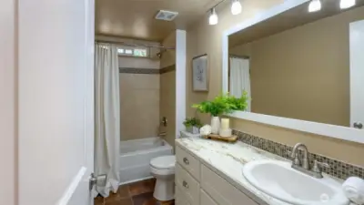 Guest bathroom with large vanity and tile shower.