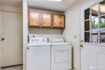 Spacious laundry room with matching washer and dryer plus overhead cabinets for easy storage.