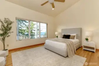 Large master bedroom with large view windows and ceiling fan