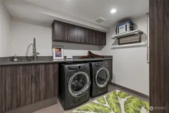 Laundry room with Electrolux steam washer & dryer.  Quartz counters with laundry sink.