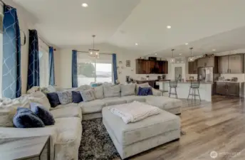 Step into an open floor plan with vaulted ceilings, recessed lighting, and oversized windows that fill the space with natural light.