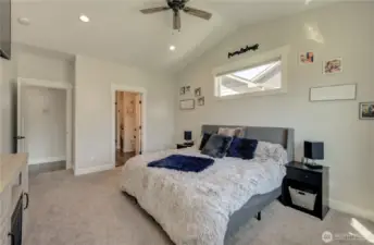 The primary suite features vaulted ceilings, a ceiling fan, oversized windows for abundant natural light, and a private ensuite bathroom.