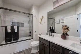 Second (guest) bathroom featuring a double sink and a tiled shower with glass enclosure.