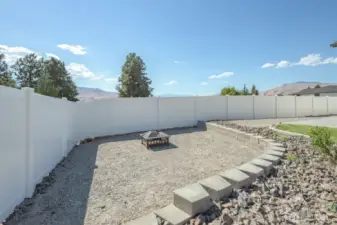 Firepit seating area set within a thoughtfully landscaped gravel space.
