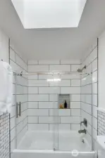 The main guest bath serves the two bedrooms on the east side of the home. Recently updated with crisp subway tile and custom glass shower doors. The skylight provides extra light.