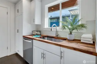 The butler's pantry/utility room with a butcher block countertop, utility sink, and a second dishwasher for your entertaining needs, plus extra cabinet and pantry storage space. The door leads to the two-car garage.