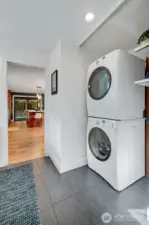The spacious laundry room with a pocket door (which can be used to separate the space) has a utility sink, a built-in storage pantry, and a second dishwasher for all your entertaining needs. To the right of the stackable washer and dryer, there is a brand new tankless water heater behind the custom panel that matches the kitchen cabinetry. Easy access to the two-car garage with extra built-in storage from the home.