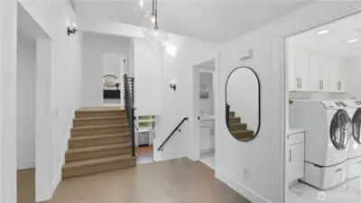 Stairs up lead to the primary bedroom, stairs down to the guest suite. Convenient laundry room to the right.
