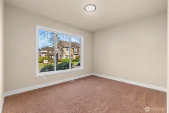 The second bedroom is bright and airy, featuring large windows that flood the space with natural light.