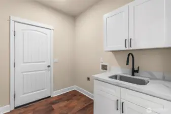 A dedicated laundry room conveniently located off the great room and garage, featuring new cabinets, quartz countertop, sink, faucet, lighting, and direct access to the garage with a new door.