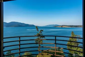 Panoramic views stretch across the islands and waterways, a vista that changes with every tide and season. This view is from the deck off the office which is on the upper floor with a private powder room, fireplace, and is accessed by the elevator or stairs.  The deck was designed to mimic a ship Captain's view of Guemes Channel.